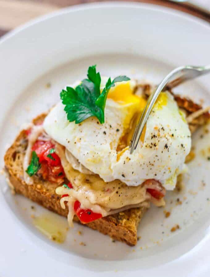 Poached Egg on Parmesan Toast is an amazing breakfast option. Soft runny egg yolk on the tomatoes and herbs with almost crusty parmesan topping makes for irresistible perfect breakfast bite.