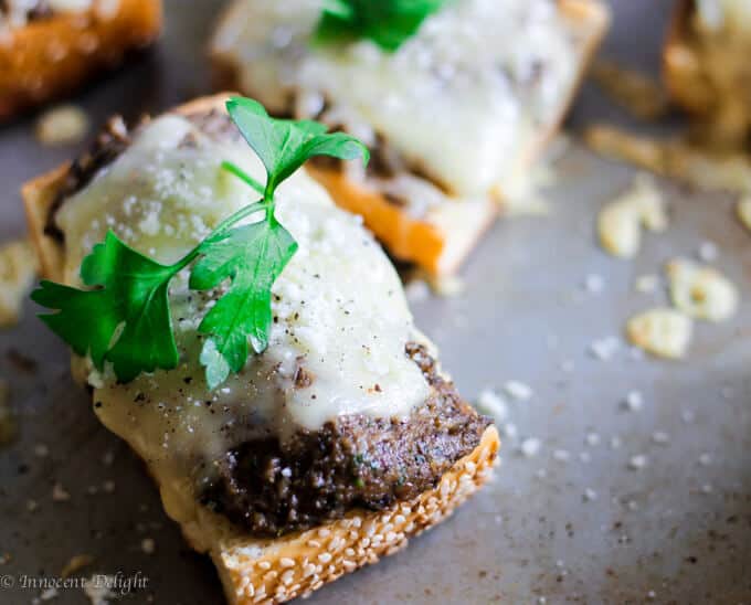 Mushroom pesto toast with fontina cheese and parsley on a baking sheet.