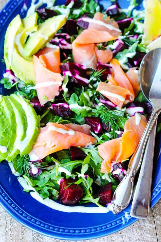 Smoked Salmon and Roasted Beets Salad with Avocado and a Goat Cheese Dressing on a blue plate with spoon and fork