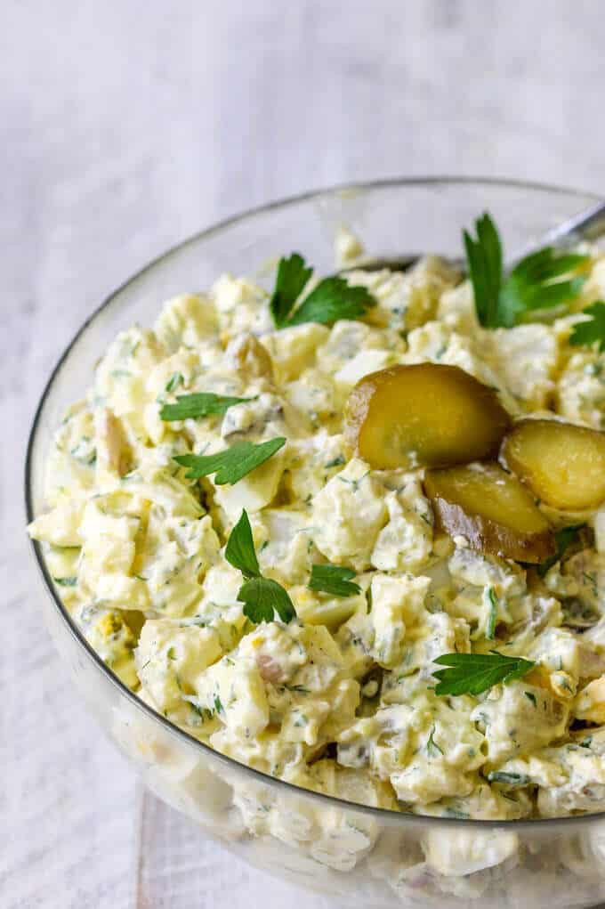 Polish Potato Salad with Eggs and Pickles in a bowl with sliced pickles on top