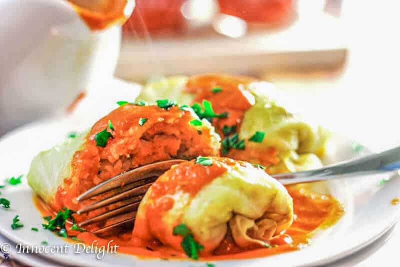 Golabki on a white plate with fork and red tomato sauce