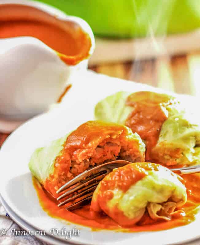 Polish Stuffed Cabbage Rolls On white plate with tomato sauce and fork