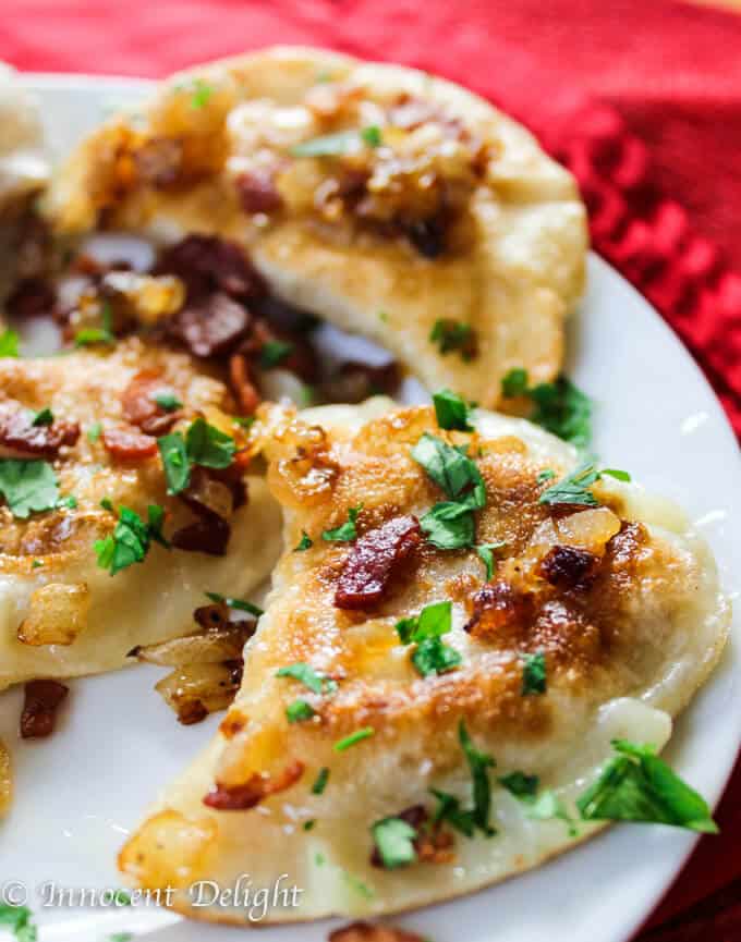 Authentic polish pierogi with potatoes and cheese on a plate with bacon and scallion