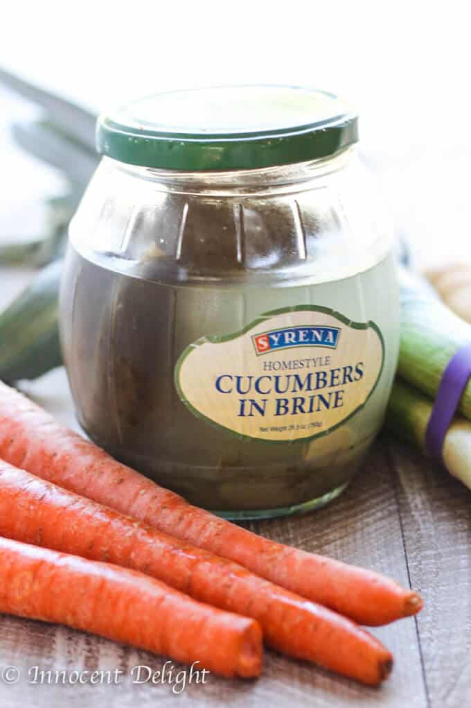 Jar of pickles in brine, carrots on a side.