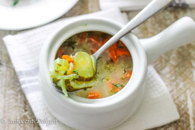 Dill pickle soup in a white bowl standing on a kitchen towel 