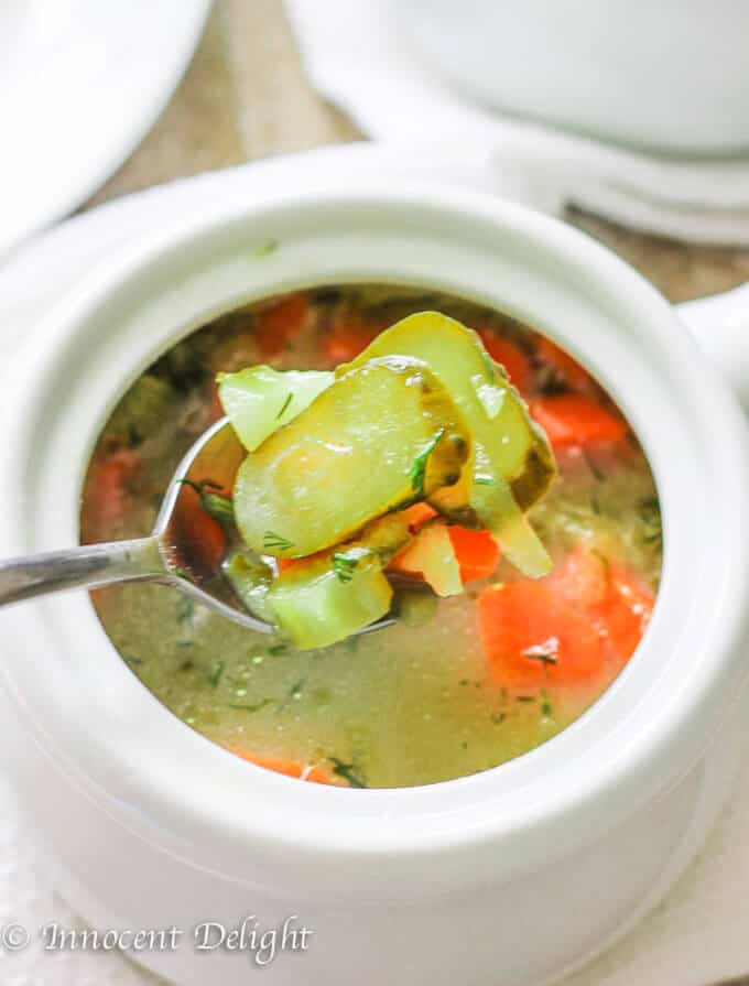 Pickle soup in a bowl with pickles on a spoon