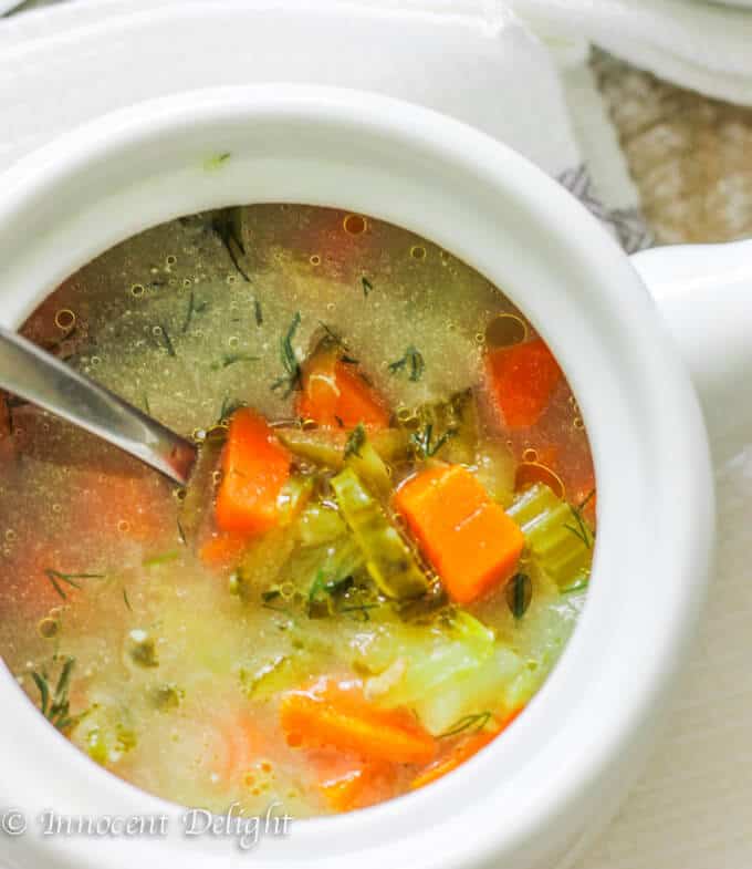 Dill pickle soup in white bowl with spoon 