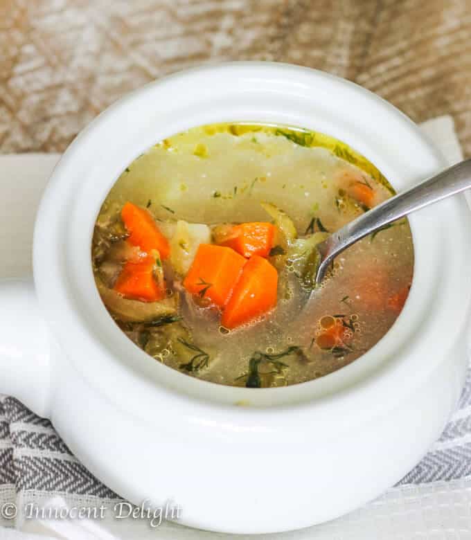 Soupe de cornichons dans un bol blanc avec une cuillère à l'intérieur, debout sur un torchon de cuisine