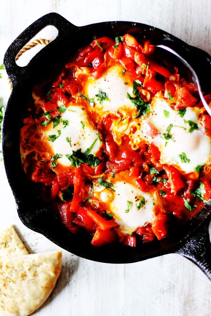 Shakshuka Classic Mediterranean Breakfast in cast iron skillet with pita bread on a side