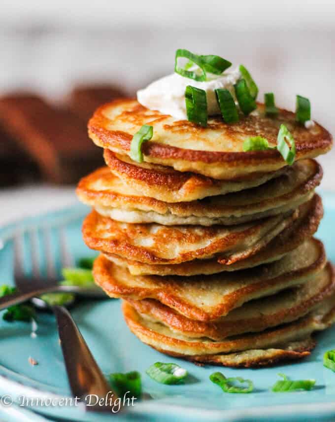 Potato Pancakes (European Style) on a blue plate stock up with dollop of sour cream and scallions. 