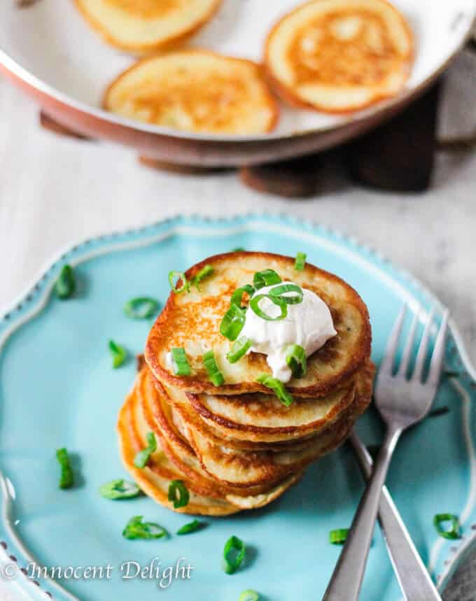 Overhead photo of potato pancakes with sour cream and scallions on top.