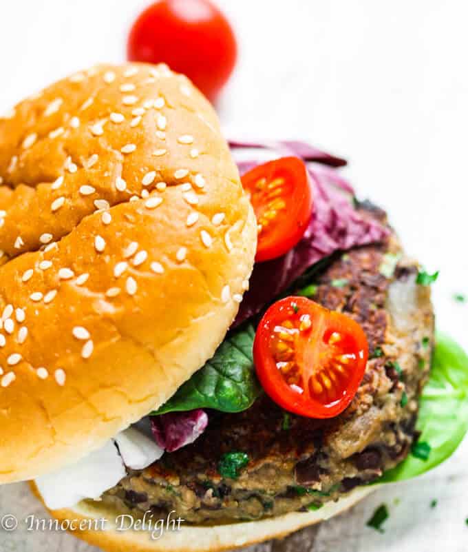 Mushroom Veggie Burger with black beans, topped with spinach and tomatoes on a bun 