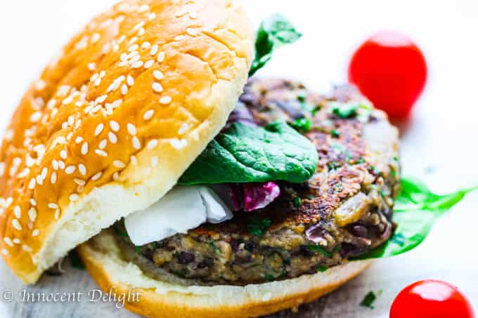 Mushroom burger with black beans on a bun with tomatoes on a side