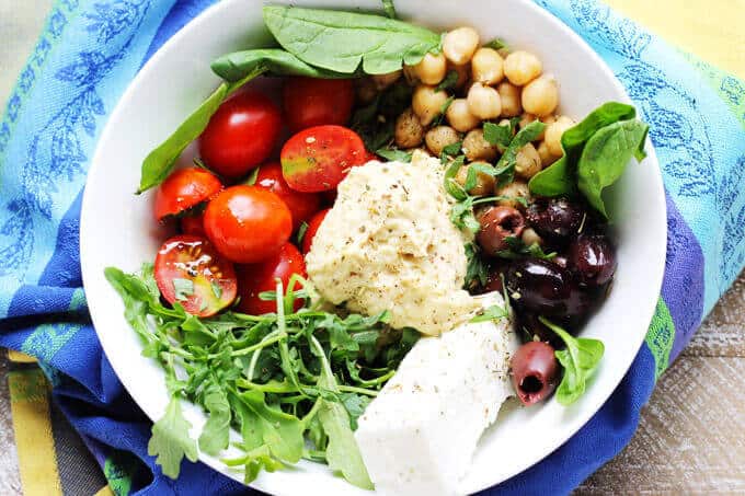 Mediterranean Hummus Bowl -on a kitchen towel with tomatoes, spinach, chickpeas and feta