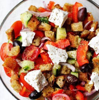 Greek Panzanella Salad combines traditional Greek salad flavors, like Kalamata olives, and tangy feta with bread cubes toasted in tasty garlicky vinaigrette.