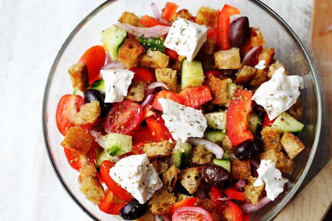 Greek Panzanella Salad combines traditional Greek salad flavors, like Kalamata olives, and tangy feta with bread cubes toasted in tasty garlicky vinaigrette.