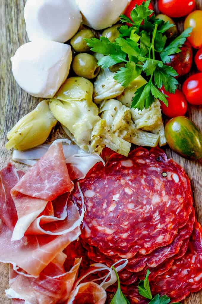 Ingredients for antipasto skewers: cured meats, olives, artichokes, tomatoes, mozzarella