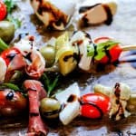Italian Antipasto Skewers are perfect little bites of traditional Italian appetizer on a stick. Delicious combination of cured meats, mozzarella balls, marinated artichoke hearts, cherry tomatoes and olives drizzled with the balsamic reduction makes for one awesome crowd pleaser.