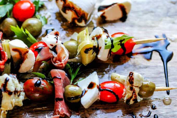 Italian Antipasto Skewers are perfect little bites of traditional Italian appetizer on a stick. Delicious combination of cured meats, mozzarella balls, marinated artichoke hearts, cherry tomatoes and olives drizzled with the balsamic reduction makes for one awesome crowd pleaser.