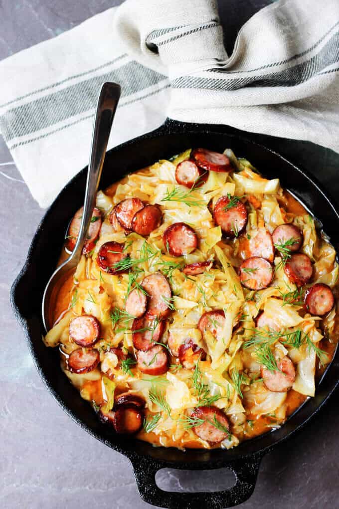 Kielbasa and Cabbage in a skillet with kitchen towel