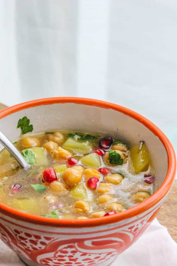 Revithosoupa is a traditional Greek vegan soup that uses simple ingredients like chickpeas, tomatoes and pomegranates. In a bowl with spoon