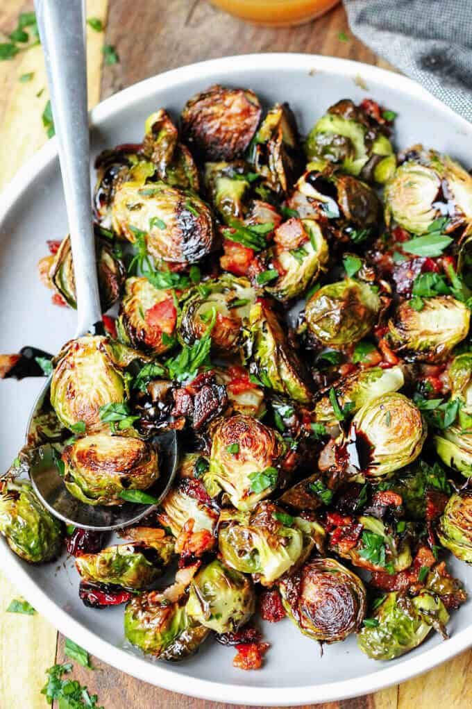 Balsamic Glazed Brussels Sprouts with Bacon, cranberries on a plate with spoon.