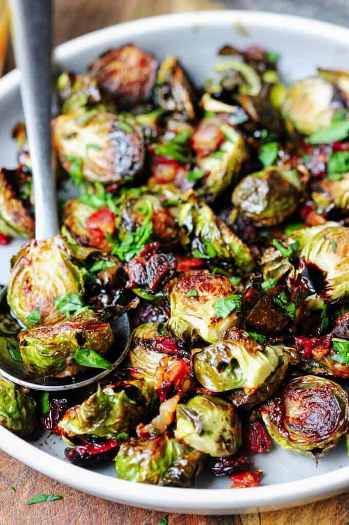 Brussels Sprouts with Balsamic glaze, cranberries and bacon on a plate with spoon