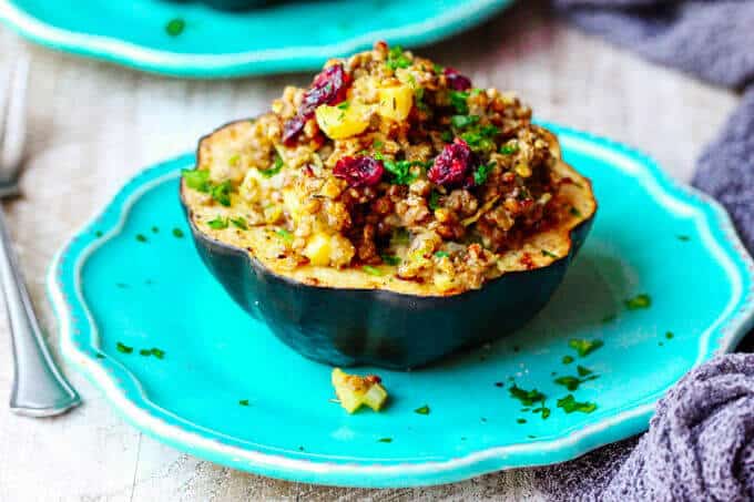 Lentils Stuffed Acorn half Squash with apples and dried cranberries on a blue plate
