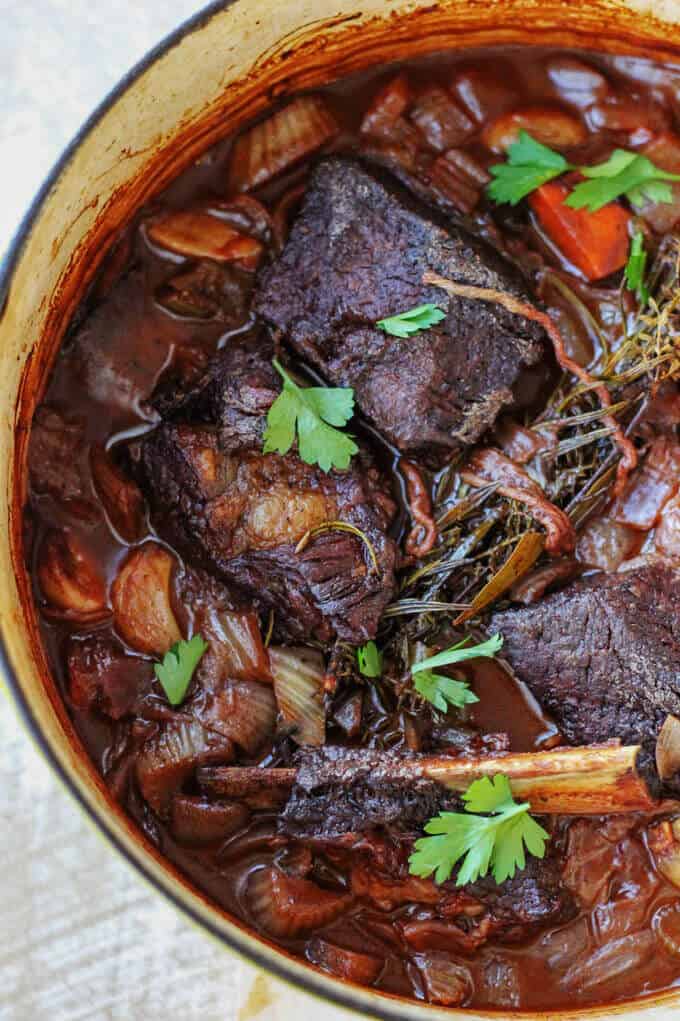 Red Wine Braised short ribs in a pot with vegetables and herbs