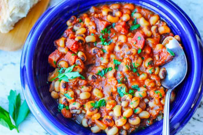 close up photo of breton beans with sausage and tomatoes on a blue plate with spoon, horizontal