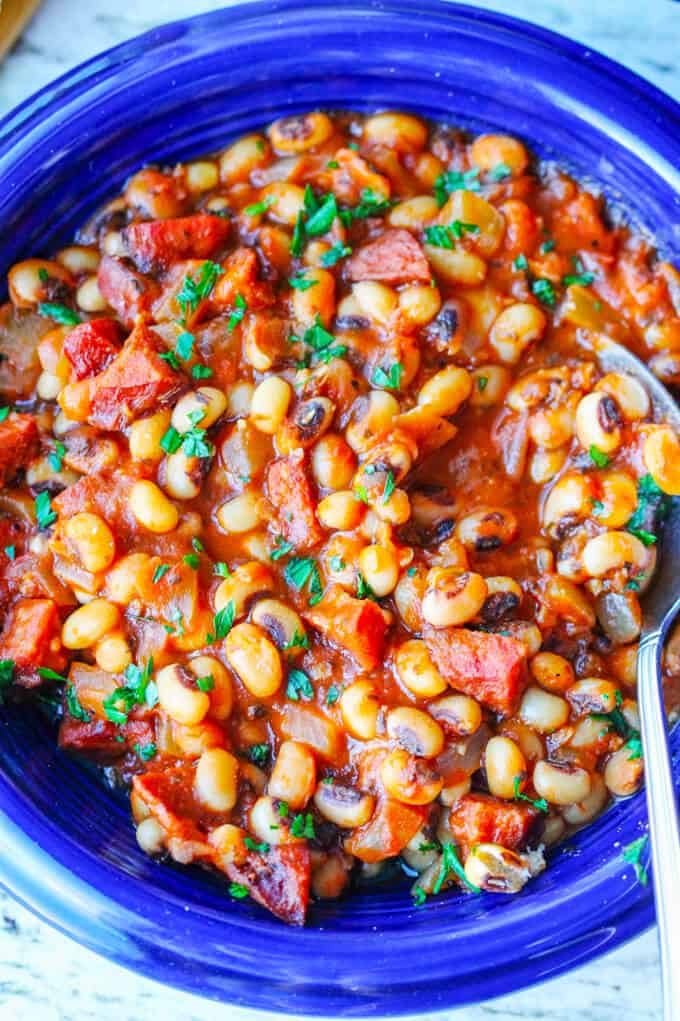 Close up photo of breton beans with sausage and tomatoes on blue plate with spoon