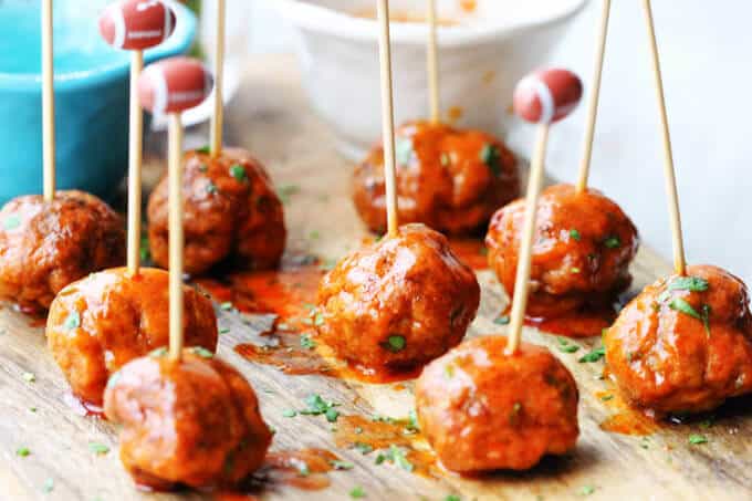 Buffalo Turkey Meatballs with football sticks and bowls with sauces in the back, vertical