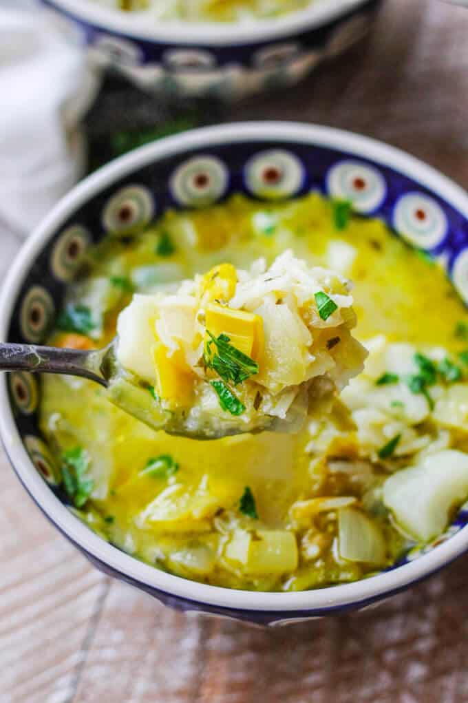 Chunky Potato Leek Soup in a bowl, close up for spoon full of chunky parts of the soup