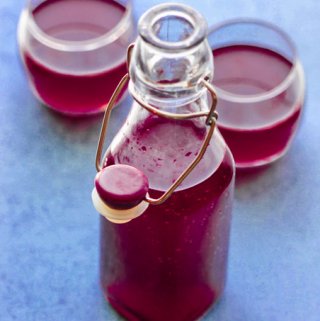 How to make beet kvass - bottle and two glasses with beet kvass ion blue background, vertical