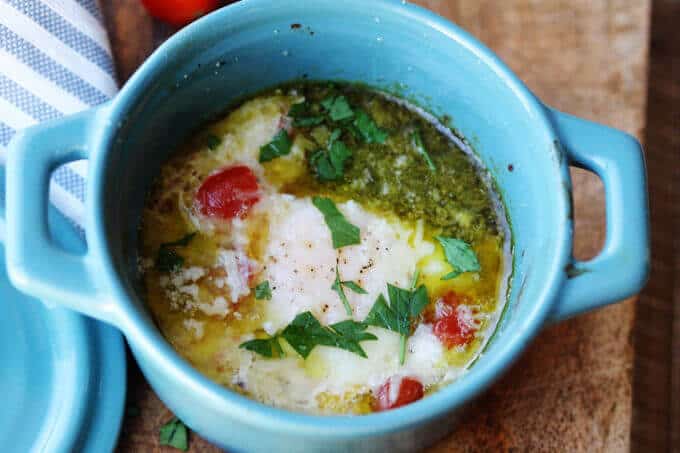 baked eggs with tomatoes and pesto in blue ramekin, horizontal shot