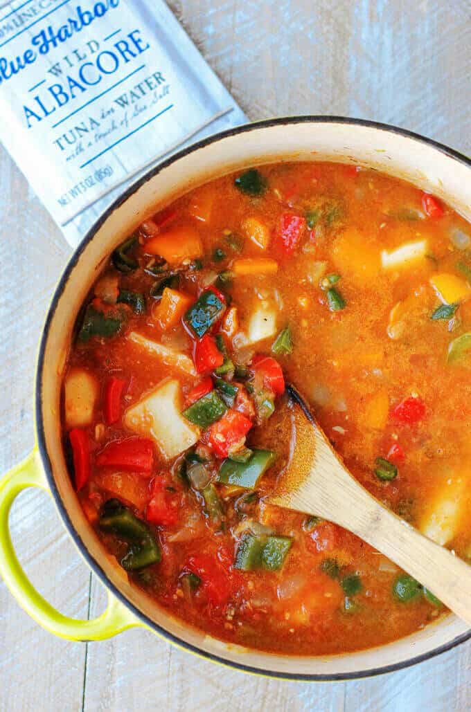 Spanish style tuna stew in a pot with wooden spoon and tuna pouch on a side 