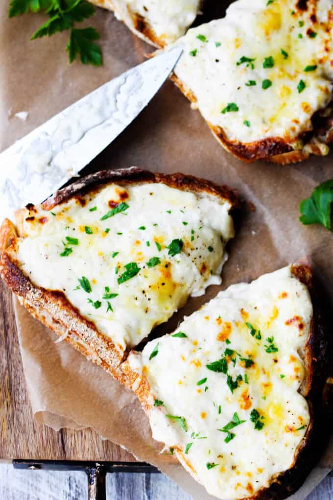 Classic Croque Monsieur sandwich with ham, cheese and béchamel, cut up in half, with the knife on a side