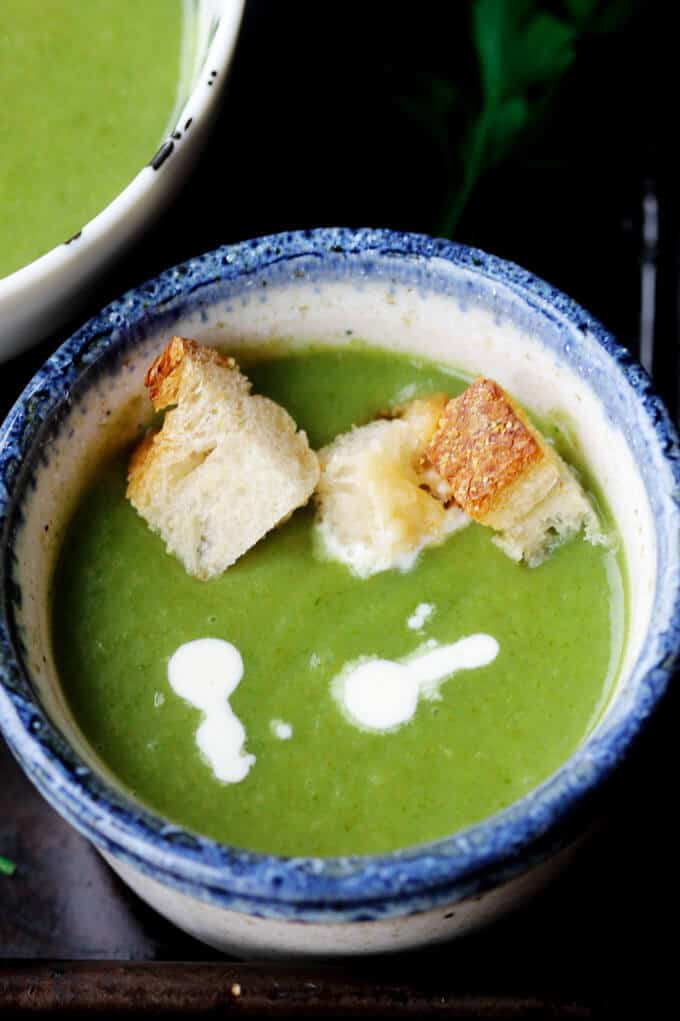 Creamy spinach soup with croutons and dollop of cream in a bowl