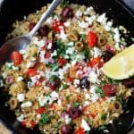Fried riced cauliflower with Mediterranean twist in a skillet with spoon and lemon