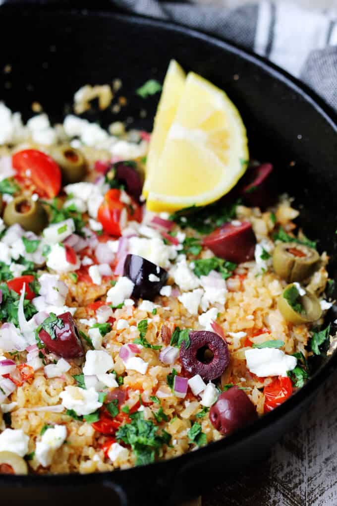 Cauliflower Fried Rice Mediterranean with feta, olives, tomatoes, lemon and parsley, close up shot