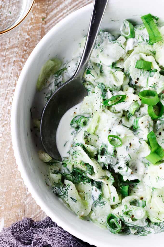 Polish cucumber salad in a bowl with spoon in it; overhead close up shot