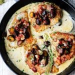 Pork chops in creamy white wine sauce with mushrooms and bacon in a pan, overhead, horizontal shot