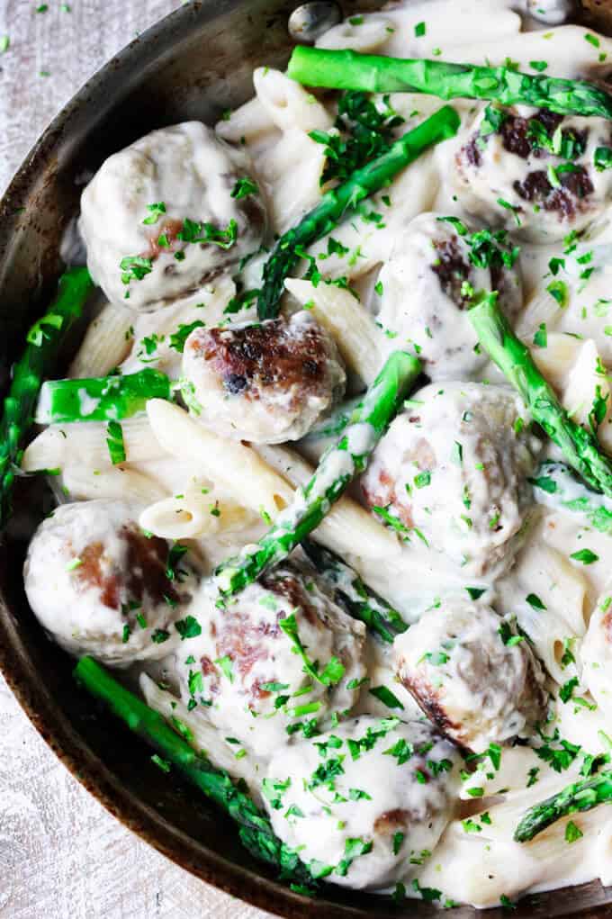 Turkey meatballs alfredo pasta with asparagus in a pan, overhead shot