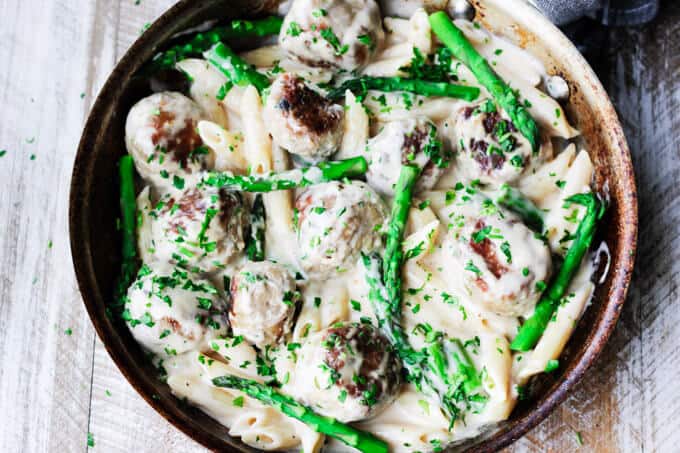 turkey meatballs and asparagus in creamy Alfredo sauce in a pan; overhead horizontal shot
