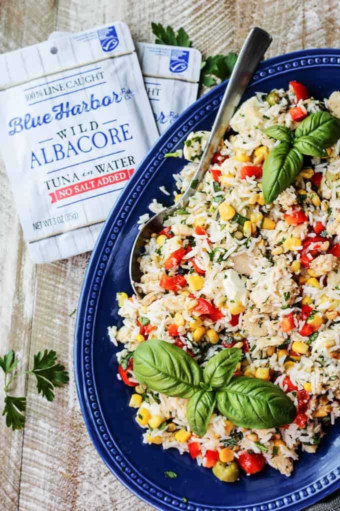 Italian Rice Salad with tuna on a blue plate with tuna pouches on a side