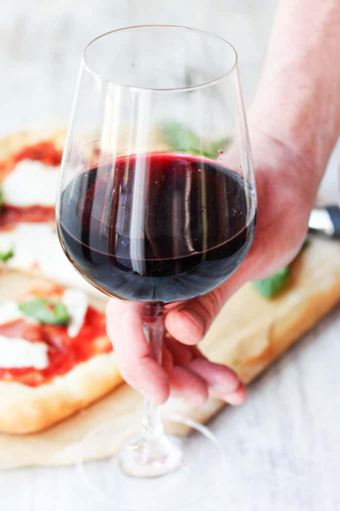 Glass of red wine with pizza in a background
