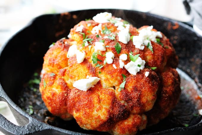 Whole roasted cauliflower head in a skillet