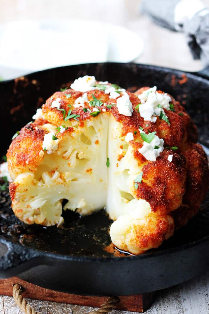 Cut up roasted head of cauliflower with feta and spices.