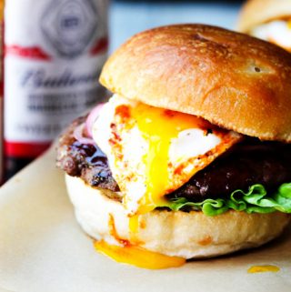 Smoky BBQ burger with runny egg yolk and sauces in the back