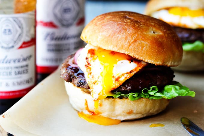 Smoky BBQ burger with runny egg yolk and sauces in the back